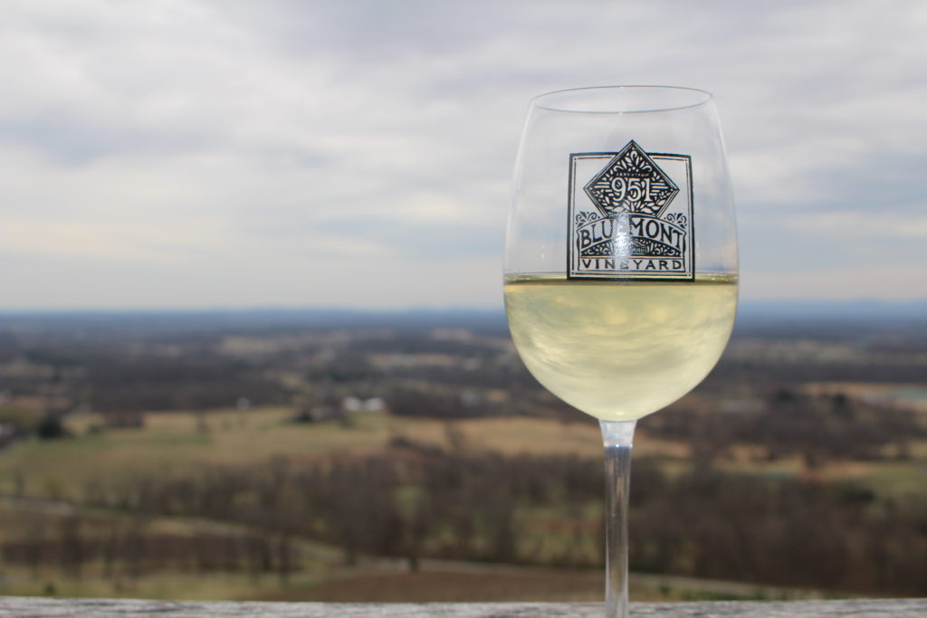 A glass of wine from Bluemont Vineyard with the scenic mountain view beyond